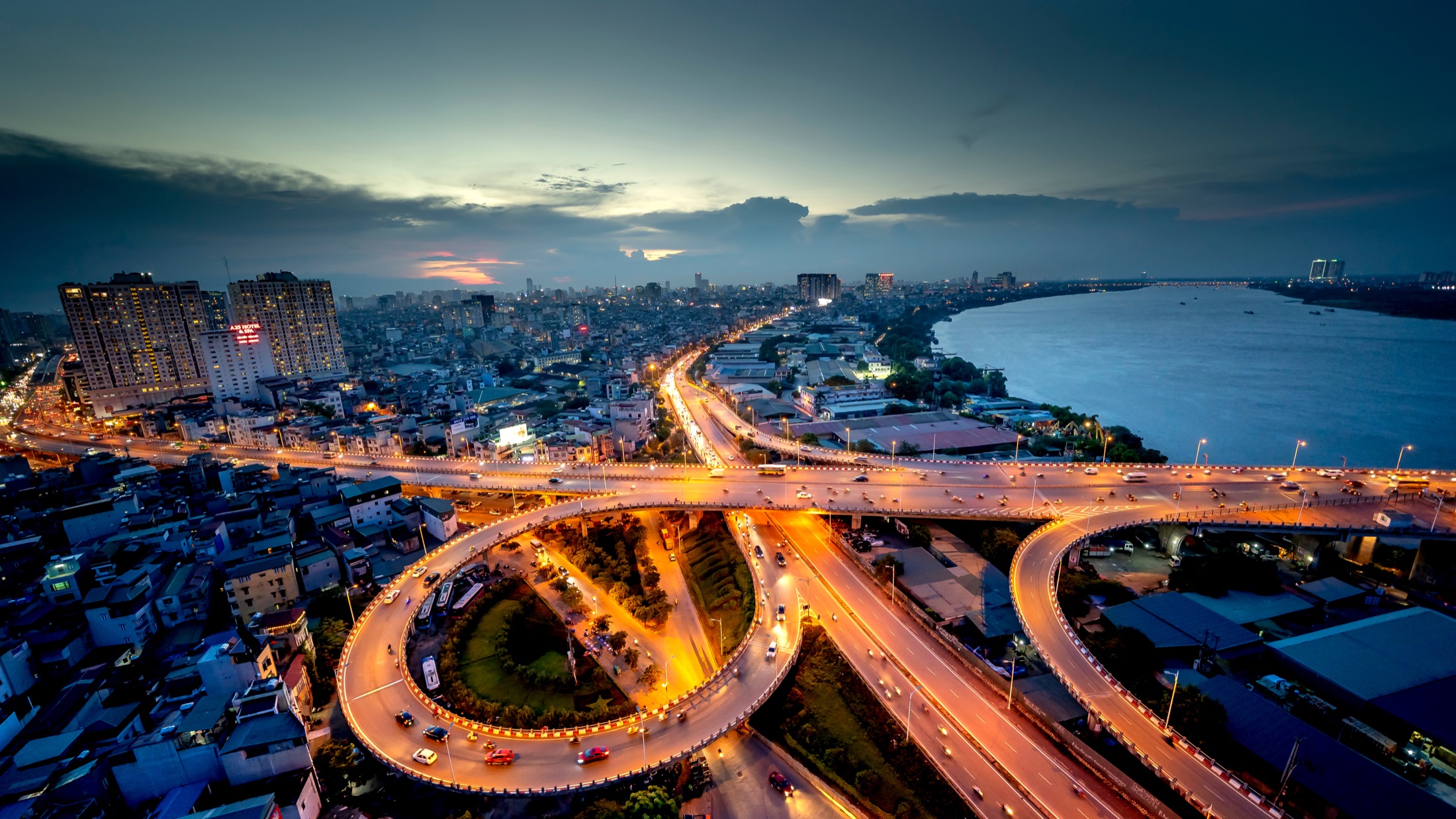 An illuminated city road branching across an urban landscape at dusk